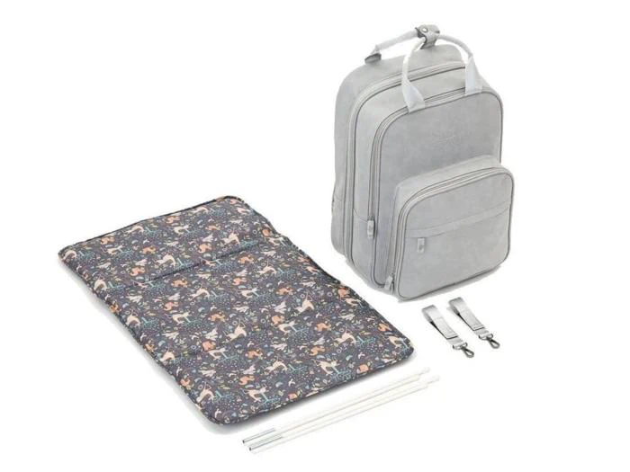 En lysegrå rygsæk med forlommer, et farverigt pusleunderlag med dyremønster, to stropper og to hvide stænger, alt sammen vist på en hvid baggrund.