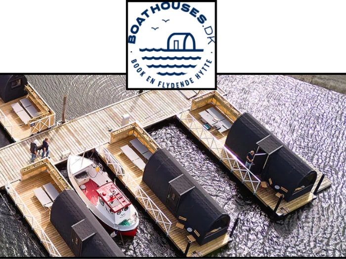 Luftfoto af flydende bådhuse og en kaj med mennesker og en båd; ovenover ses Boathouses.dk-logoet med en båd og bølger.