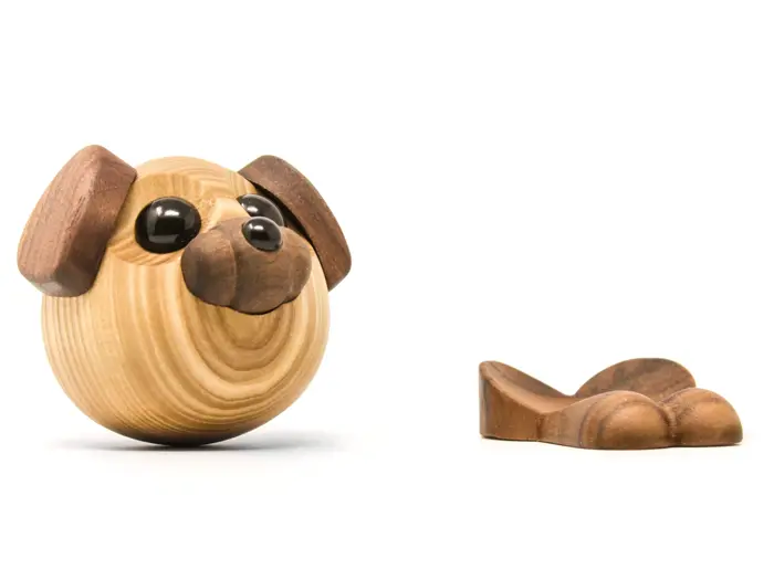 Et rundt hundehoved af træ med mørke ører og næse sidder ved siden af et separat træstykke formet som hundepoter.