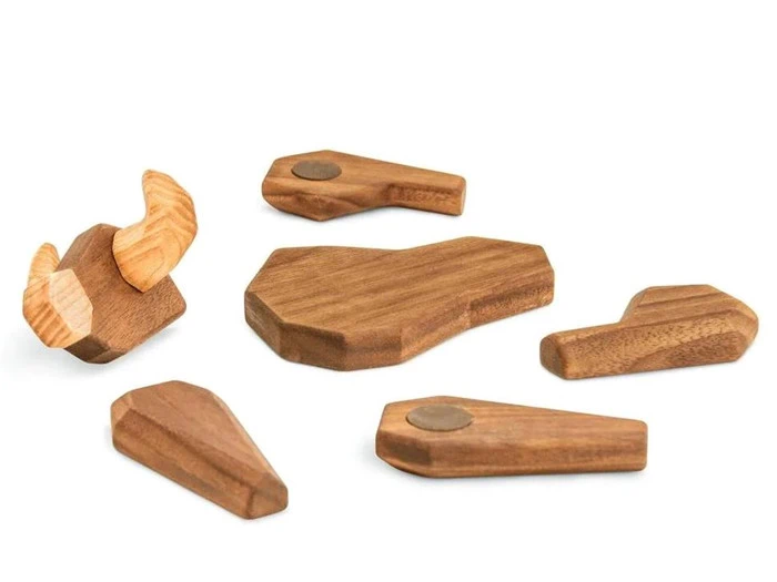 Seks geometriske former af træ, hvoraf den ene ligner et bøffelhoved med buede horn, og de andre er abstrakte, kantede stykker, som alle er placeret på en hvid baggrund.