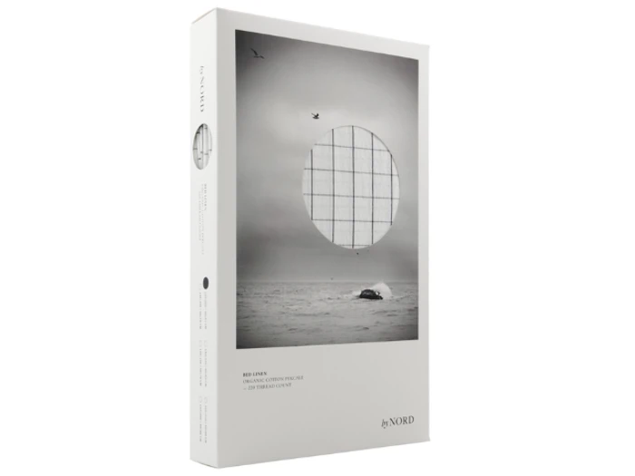 Et vægkunsttryk i æske fra byNORD med en sort-hvid havscene med en fugl på himlen og en hval, overlejret med et cirkulært gitterdesign.