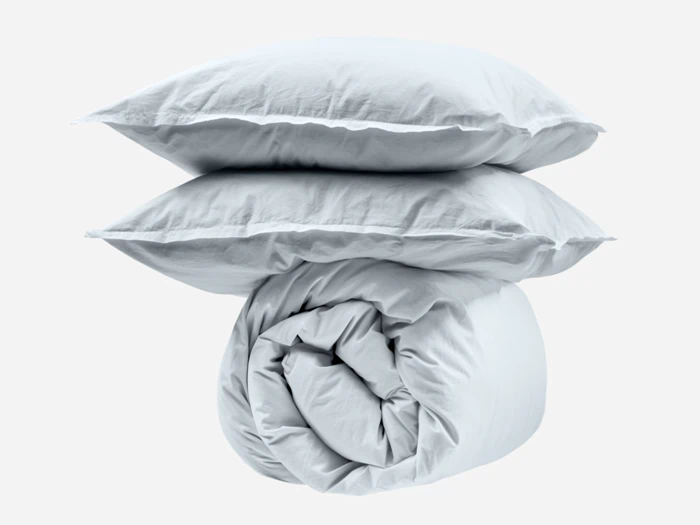 To hvide puder stablet oven på en pænt rullet hvid dyne, alt sammen mod en almindelig hvid baggrund.