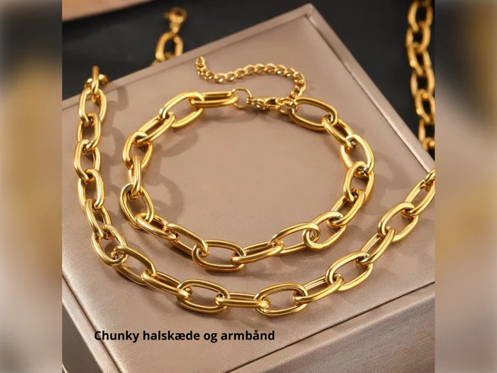 En chunky guldkæde og et armbånd vises på en beige æske. Teksten chunky halskæde og armbånd vises i nederste venstre hjørne.