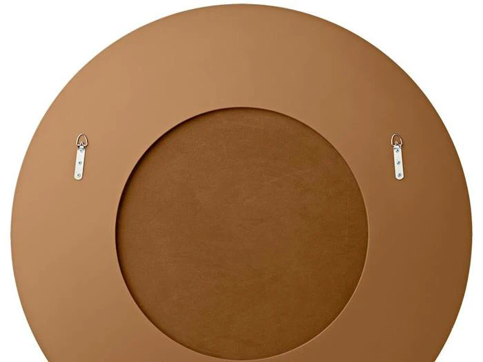 Rund, brun genstand med en forsænket midte, set ovenfra, med to sølvfarvede ophængsbeslag nær toppen.