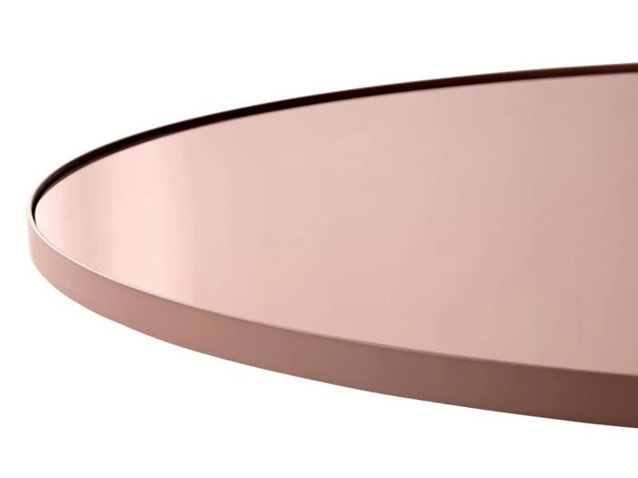 Nærbillede af en rund, pink metalbakke med hævet kant mod en hvid baggrund.