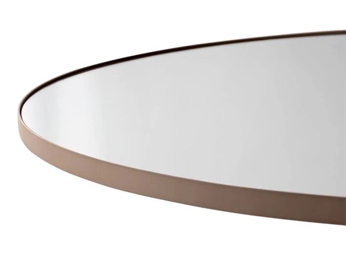 Nærbillede af kanten af et rundt spejl med en tynd, brun metalramme mod en hvid baggrund.