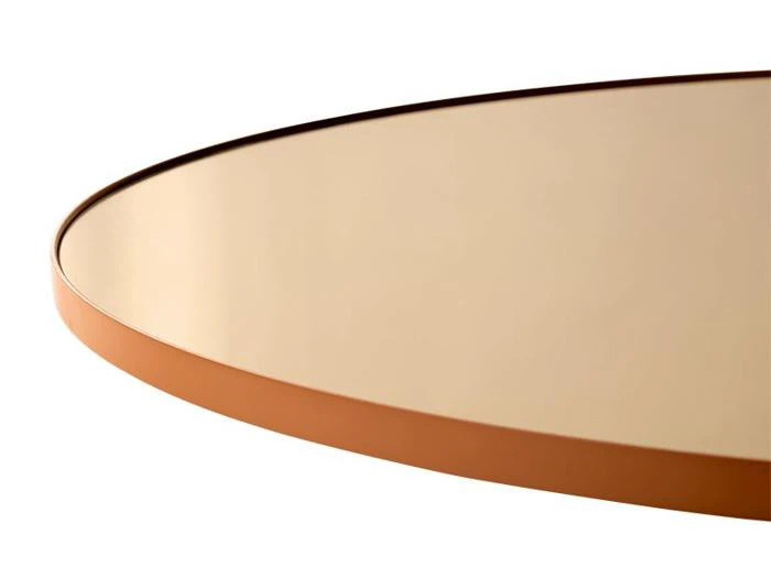 Nærbillede af et rundt bord med en glat, reflekterende beige overflade og en tynd, brun kant mod en hvid baggrund.