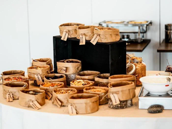 Kurve fyldt med forskellige tørrede frugter og nødder, der alle er mærket, er anbragt på et bord, så de udgør en snackbuffet.