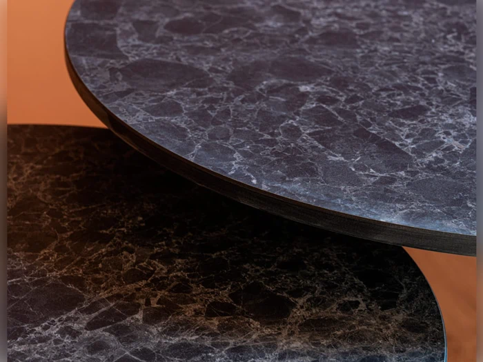To overlappende runde bordplader med en mørk, marmoreret overflade på en varm brun baggrund.