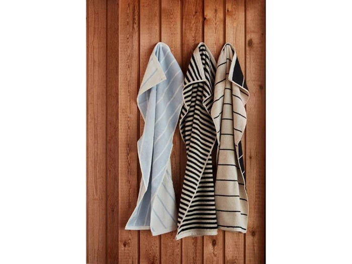 Tre håndklæder med forskellige stribede mønstre hænger på kroge på en trævæg.