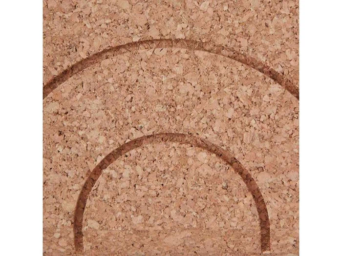 Nærbillede af en korkoverflade med to mørkebrune halvcirkelformede buer, der er ætset ind i den og danner et geometrisk mønster.