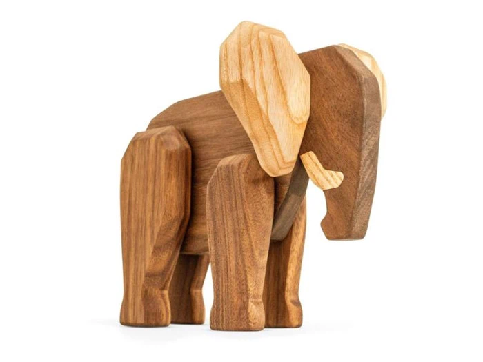 En elefantfigur af træ med udskårne geometriske former og glatte, naturlige trækorn, som står på en hvid baggrund.