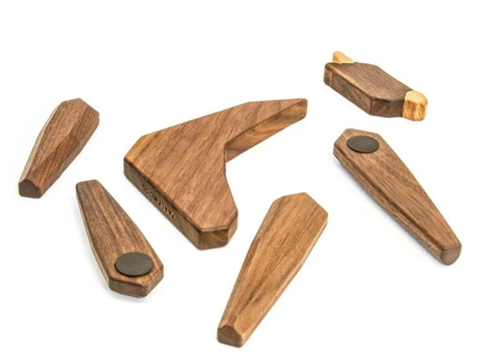 Seks geometriske træstykker med glatte kanter, nogle med sorte runde magneter, arrangeret på en hvid baggrund.