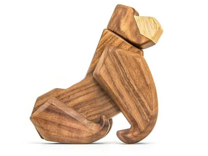 En træskulptur af en gorilla, der sidder med armene hvilende på knæene, fremstillet af glat, lysebrunt træ.