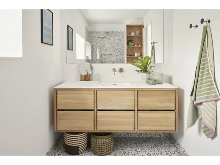 Moderne badeværelse med svævende kommode i træ, stort spejl, planter, stribet håndklæde på krog og flettede kurve under vasken. Vægge og gulv har et hvidt og spættet design.