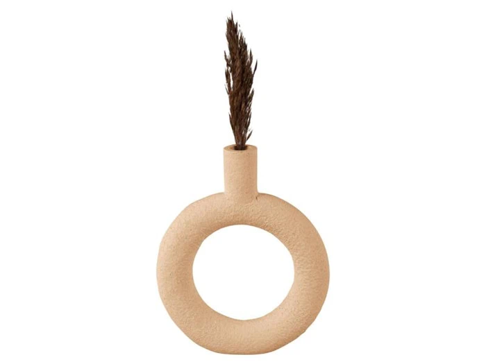 En beige, rund keramikvase med en hul midte og en smal hals, der holder en enkelt tørret, brun græsstængel.