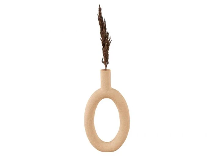 En beige, oval keramikvase med en åben midte, der holder en enkelt tørret brun græsstængel på en hvid baggrund.