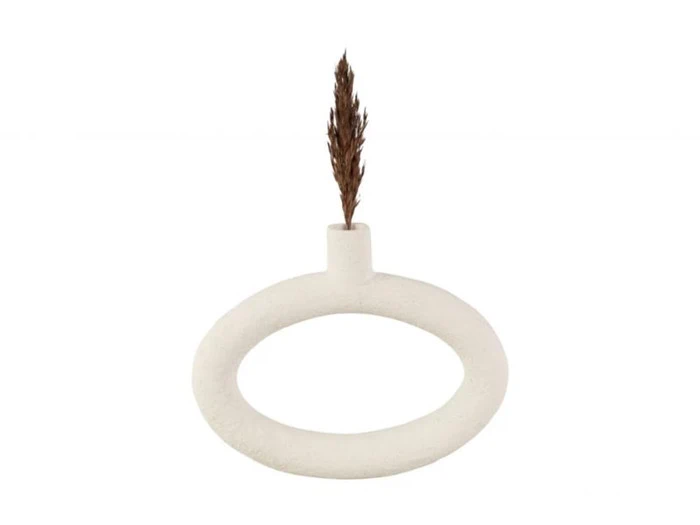 En minimalistisk hvid cirkulær vase med et enkelt tørret brunt siv placeret i den lille åbning i toppen mod en almindelig hvid baggrund.