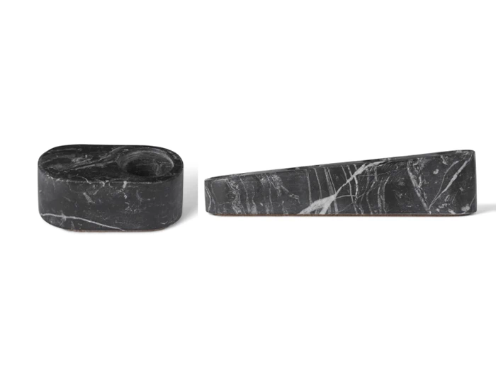To objekter af sort marmor med hvide årer: det ene er en oval form med en lille cirkulær fordybning, og det andet er en lang, smal kile. Begge er placeret på en hvid baggrund.