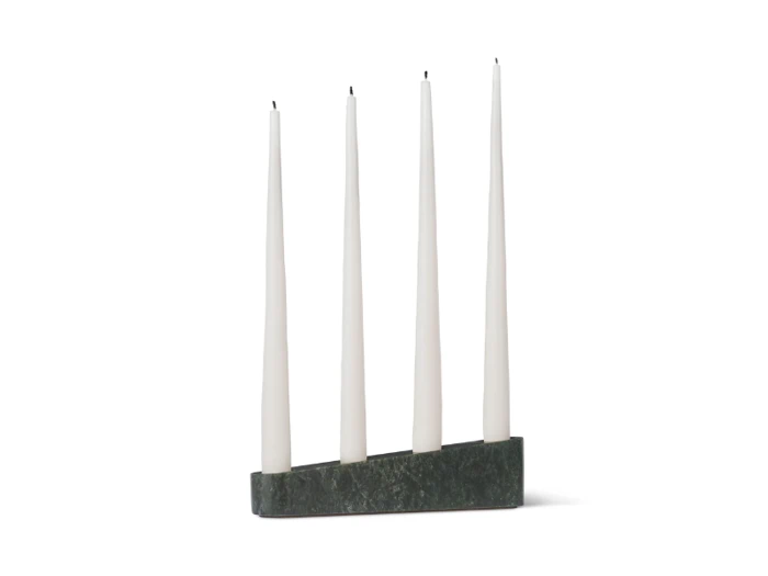 Fire hvide bloklys er placeret lodret i en mørk rektangulær marmorholder, jævnt fordelt i en række mod en hvid baggrund.