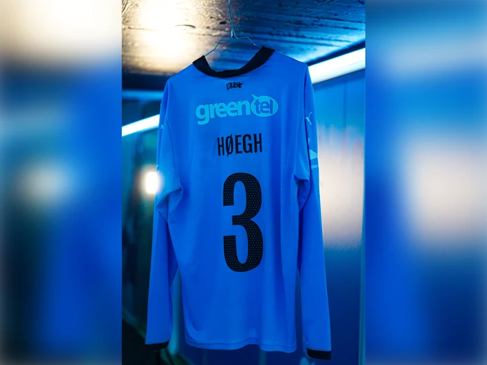 Lyseblå langærmet trøje med GREENTEL, HØEGH og tallet 3 på ryggen.