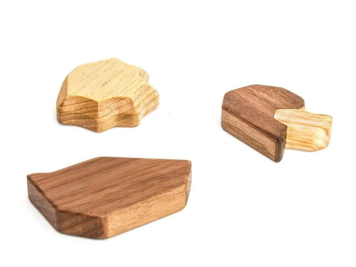 Tre uregelmæssigt formede træklodser i forskellige brune nuancer er arrangeret på en hvid baggrund.