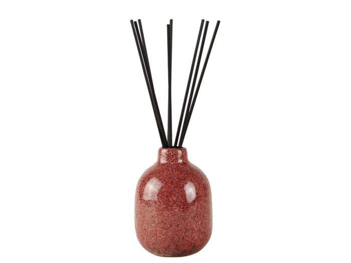 En rødbrun keramisk diffusorflaske med flere tynde sorte sivpinde anbragt lodret indeni.