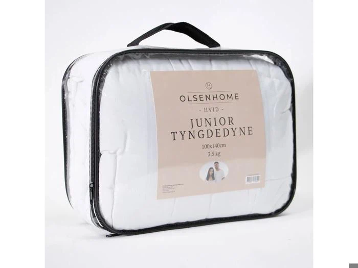 En indpakket OlsenHome juniordyne, 100x140 cm og 3,5 kg, med sort håndtag og klar front, der viser produktetiketten på dansk.