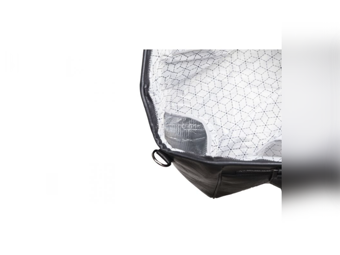 Åbent billede af en sort taske med hvidt, mønstret inderfor og en synlig inderlomme på den ene side.