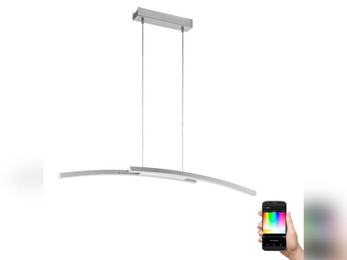 En moderne, buet LED-pendel, der hænger ned fra loftet, med en hånd, der holder en smartphone, som viser en app til farvevalg.