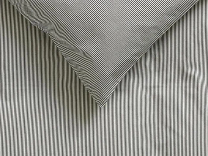 Et nærbillede af en pude og et lagen med tynde, lodrette sorte og hvide nålestriber, der er arrangeret på en pæn måde.