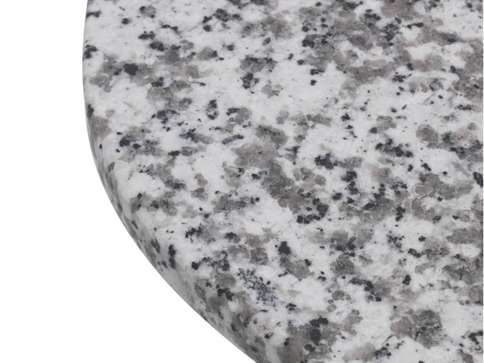 Nærbillede af den afrundede kant på en poleret granitoverflade med et hvidt, gråt og sort plettet mønster.