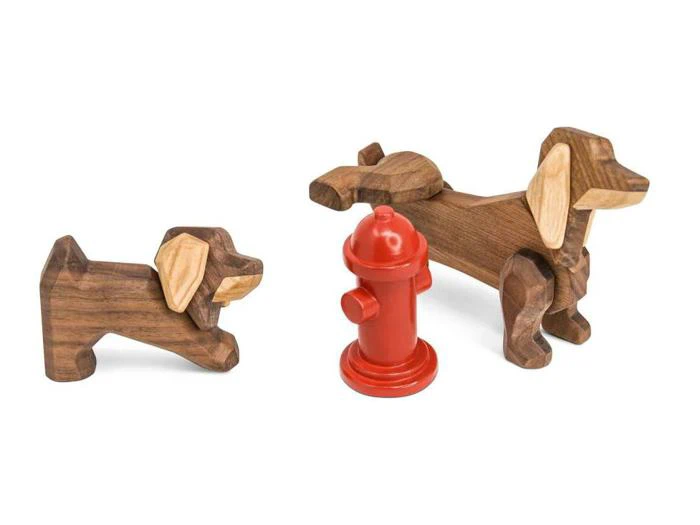 To hundefigurer af træ og en lille rød brandhane er placeret på en hvid baggrund.