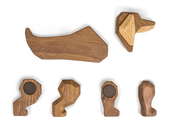 Fem træstykker, der er arrangeret, så de ligner en hunds krop, hoved og ben; benene har mørkere, runde detaljer, der forestiller poter.