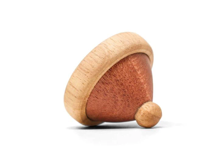 En snurretop af træ med en lys kant og spids og en mørkere træmidte, der hviler på siden mod en hvid baggrund.