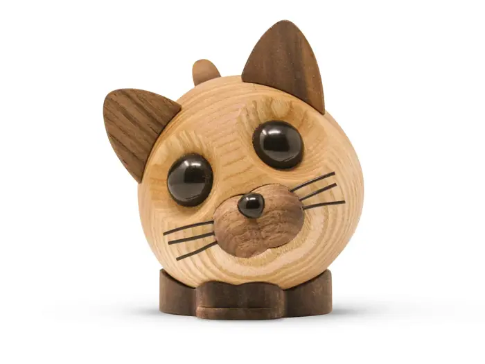 En rund kattefigur i træ med store sorte øjne, mørkebrune ører, næse og knurhår på en hvid baggrund.