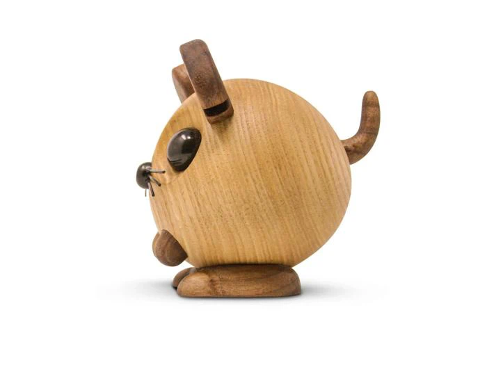 En rund kattefigur af træ med ører, hale, fødder og næse af mørkt træ, sorte knurhår og store sorte øjne, vist i profil på en hvid baggrund.