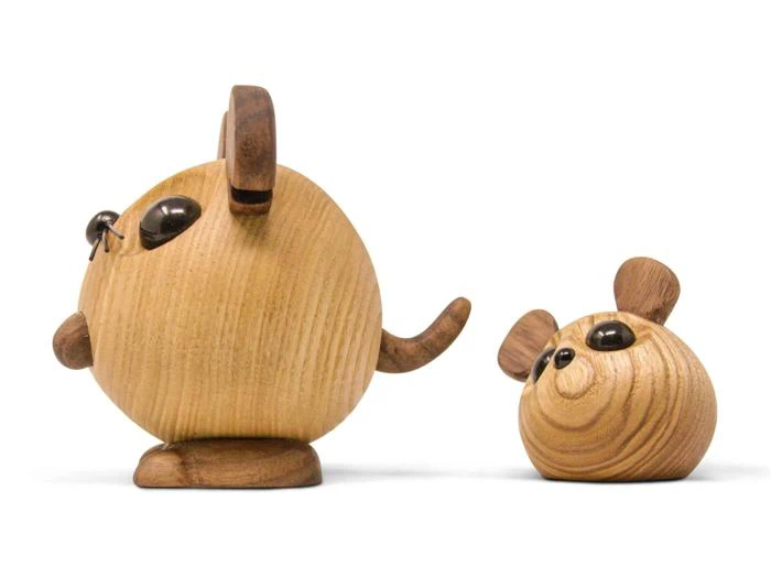 To dyrefigurer af træ, den ene ligner en rund kat, der står oprejst, og den anden en lille rund mus, begge med store sorte øjne og udskårne træører, på en hvid baggrund.