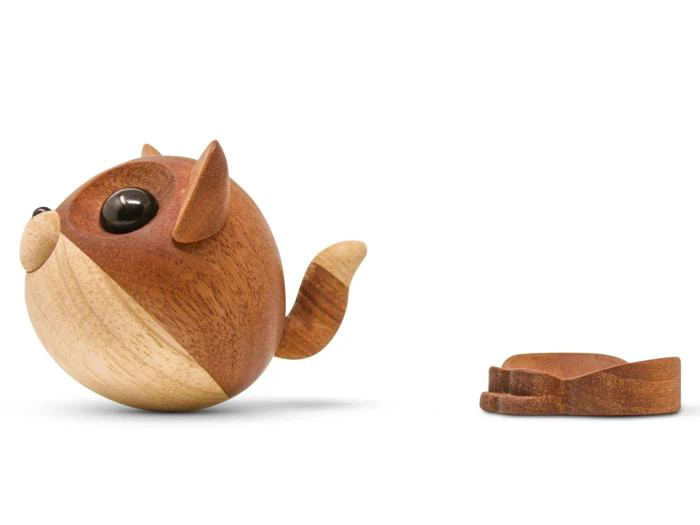 En lille, rund vaskebjørnsfigur af træ med store øjne står oprejst ved siden af en separat træbase formet som vaskebjørns poter på en hvid baggrund.