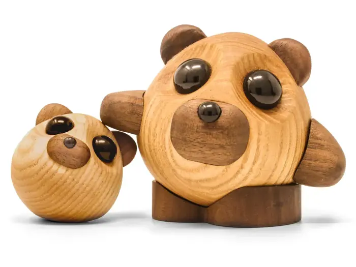 To runde pandabjørnefigurer i træ med enkle, mørke øjne og ører; den ene er større og har en arm om den mindre, begge på en hvid baggrund.
