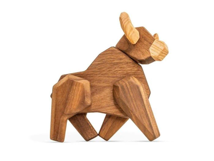 En træfigur af en tyr med forenklede, geometriske former og lysere horn, der står på fire ben.