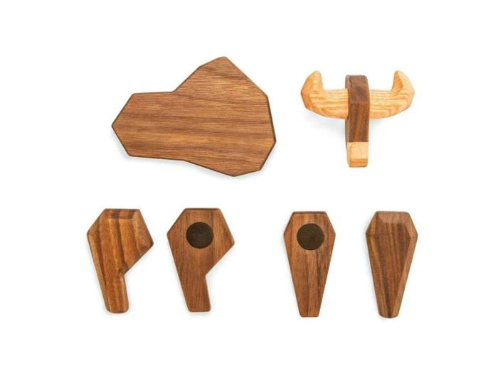 Fem geometriske vægkroge i træ og et vægophæng i træ i form af et elghoved, alle vist på en hvid baggrund.
