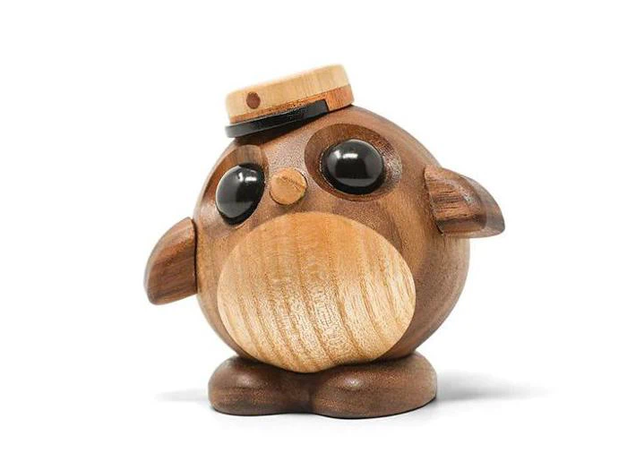 En rund uglefigur af træ med store sorte øjne, små vinger og en flad træhat, der står på to små fødder mod en hvid baggrund.
