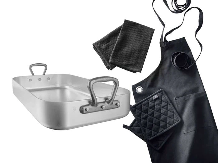 En sølvbradepande, to sorte viskestykker, et sort forklæde og en sort quiltet ovnhandske er anbragt på en hvid baggrund.