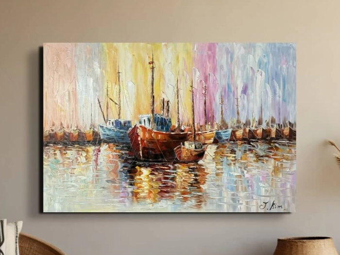 Et farverigt impressionistisk maleri af både, der ligger til kaj på vandet, med levende refleksioner og pastelfarver i blå, gul og pink i baggrunden, som hænger på en beige væg.