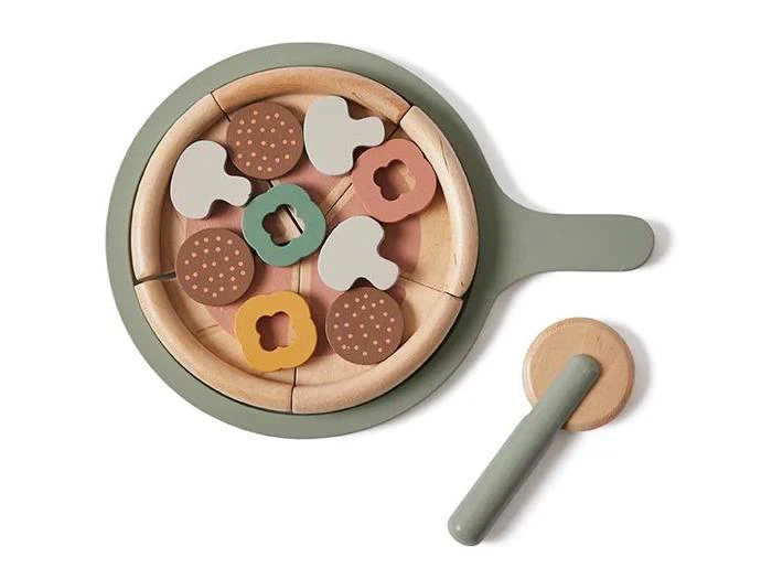 Legetøjspizza af træ med aftagelige skiver og forskelligt vegetabilsk fyld, vist i en grøn pande med en matchende træspatel på en hvid baggrund.