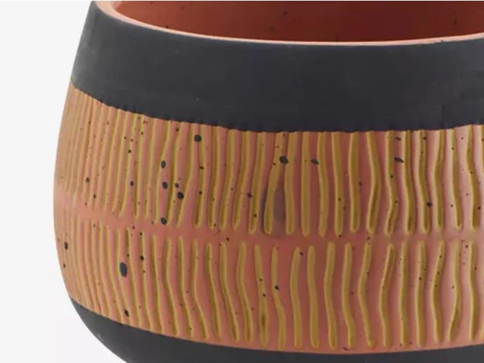 Nærbillede af en rund keramikkrukke med sort kant, rødbrun krop og gule, lodrette streger omkring midten.