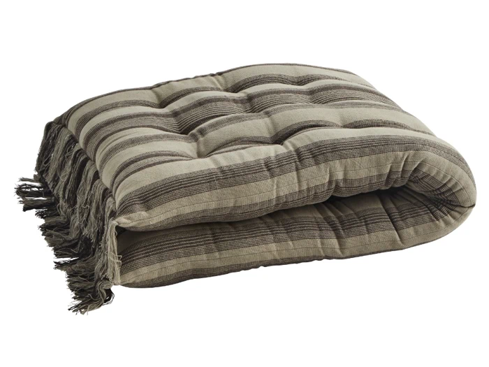 En foldet, tuftet pude eller madras med beige og brune striber og frynsede kanter, der ligger på en hvid baggrund.