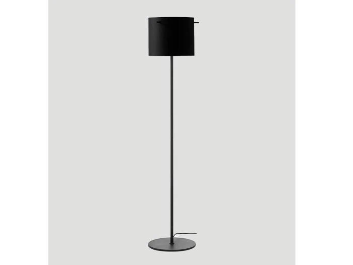Minimalistisk sort gulvlampe med cylindrisk skærm, slank stang, rund fod og synlig ledning på en almindelig lys baggrund.