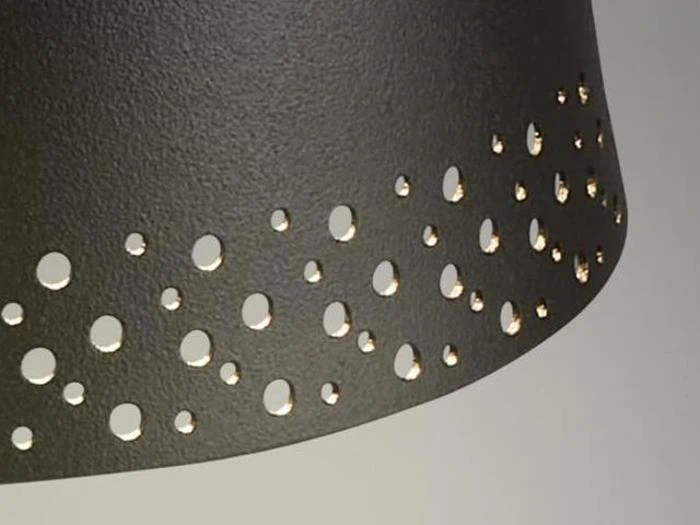 Et nærbillede af en mørk lampeskærm med små cirkulære huller, der lader lyset skinne igennem.